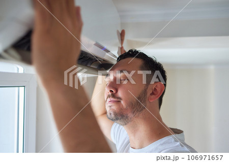 handsome man suffering from heat under air conditioner at home 106971657