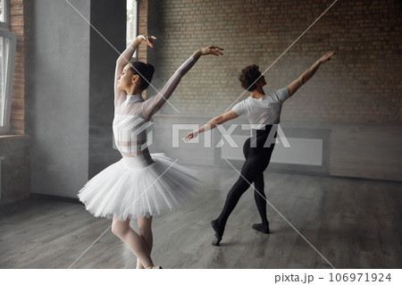 Two young ballet dancers wearing costume practicing together in studio class 106971924