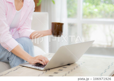 Closeup hands of business woman work from home with laptop computer and drinking coffee on sofa. 106971926