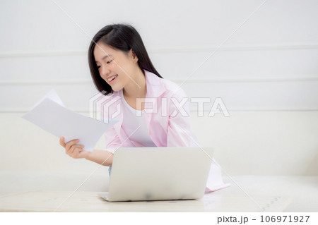 Young asian business woman working on laptop computer and looking graph and chart of report. 106971927