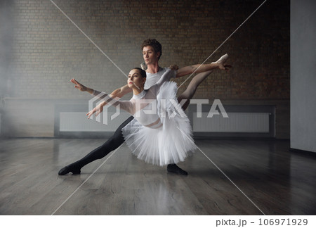 Woman and man ballet dancers in dynamic action against studio background 106971929