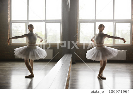 Beautiful young ballerina training classic ballet in studio with huge mirror 106971964