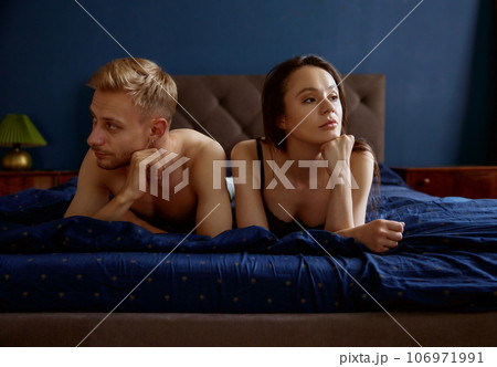 Sad unhappy couple lying in home bed having relationship difficulties Sad unhappy couple lying in home bed having relationship difficulties 106971991