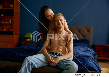 Happy smiling loving couple sitting and cuddling in bed Happy smiling loving couple sitting and cuddling in bed 106971998