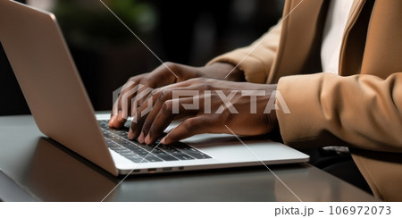 Close-up hands of an African American businessman works with laptop at sidewalk cafe. 106972073