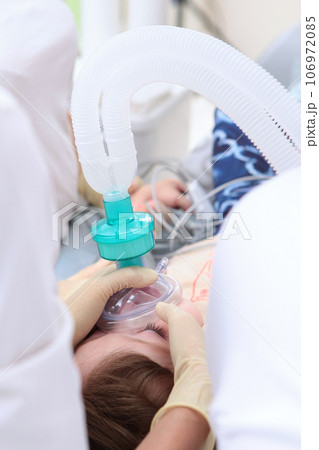 Child is under anesthesia. Breathing tube in child's mouth. Open mouth. Modern dentistry.An unrecognizable person. Vertical photo. 106972085