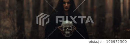 black terrible witch holds the skull of a dead man in her hands 106972500