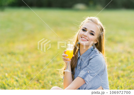 Young happy woman holds a glass of orange juice in her hand 106972700
