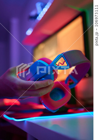 A young guy gets a phone call during an online video game, he takes off his headphones and goes to talk. 106973111