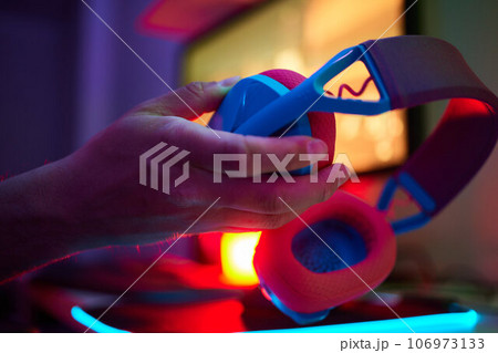 A young guy gets a phone call during an online video game, he takes off his headphones and goes to talk. 106973133