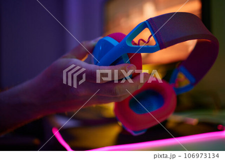 A young guy gets a phone call during an online video game, he takes off his headphones and goes to talk. 106973134
