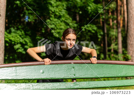 Beautiful young sporty woman in black t-shirt, black shorts and pink trainers warming up exercising triceps and chest Beautiful young sporty woman in black t-shirt, black shorts and pink trainers warming up exercising triceps and chest 106973223