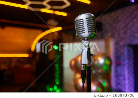Retro Microphones on front stage in pub bar or restaurant. Classic sing a song in evening and night show concert light bokeh background. 106973706
