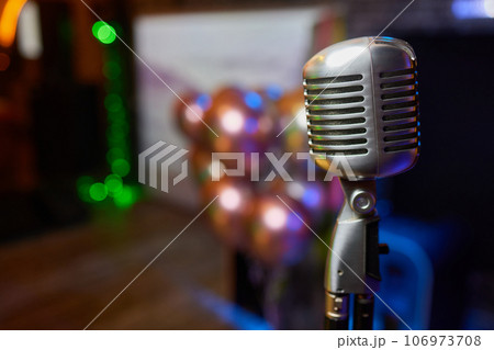 Retro Microphones on front stage in pub bar or restaurant. Classic sing a song in evening and night show concert light bokeh background. 106973708