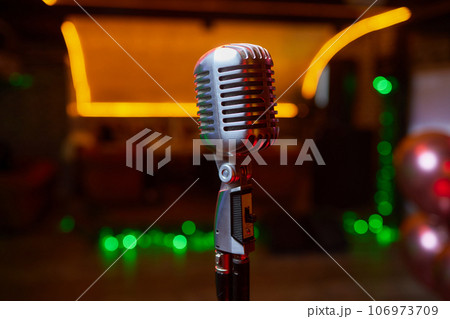 Retro Microphones on front stage in pub bar or restaurant. Classic sing a song in evening and night show concert light bokeh background. 106973709