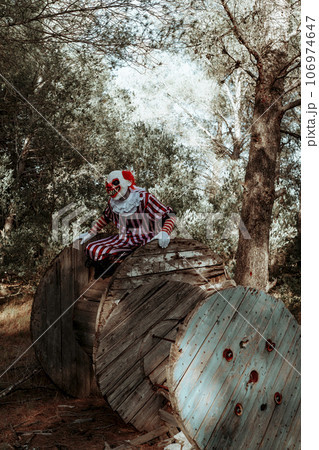 evil clown in the wood perched on a cable reel 106974647