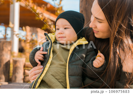 Cute little asian boy stands outdoors. Happy child walking in autumn park. Toddler baby boy wears trendy jacket and hat. Autumn fashion. Stylish child outside. Cute little asian boy stands outdoors. Happy child walking in autumn park. Toddler baby boy wears trendy jacket and hat. Autumn fashion. Stylish child outside. 106975683