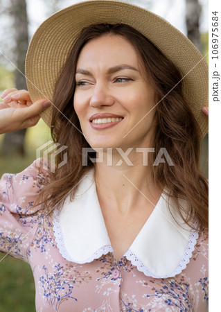A young beautiful woman in a dress and holding a hat with her hands and reading a book in nature. Romantic and vintage photo of a beautiful girl. Reading and relaxation A young beautiful woman in a dress and holding a hat with her hands and reading a book in nature. Romantic and vintage photo of a beautiful girl. Reading and relaxation 106975684