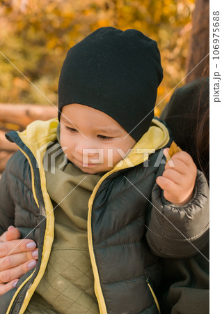 Cute little asian boy stands outdoors. Happy child walking in autumn park. Toddler baby boy wears trendy jacket and hat. Autumn fashion. Stylish child outside. Cute little asian boy stands outdoors. Happy child walking in autumn park. Toddler baby boy wears trendy jacket and hat. Autumn fashion. Stylish child outside. 106975688