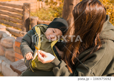Cute little asian boy with mother outdoors. Happy child walking in autumn park. Toddler baby boy wears trendy jacket and hat. Autumn fashion. Stylish child outside. Cute little asian boy with mother outdoors. Happy child walking in autumn park. Toddler baby boy wears trendy jacket and hat. Autumn fashion. Stylish child outside. 106975692