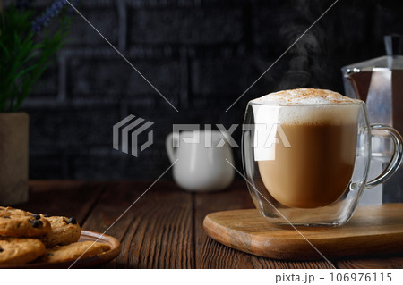 cappuccino in cup and geyser coffee maker on wooden table with black brick wall as background 106976115