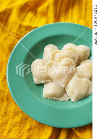 Heart-shaped ravioli lies on a green plate. Prepared food, romantic meal, surprise for your loved one. Heart-shaped ravioli lies on a green plate. Prepared food, romantic meal, surprise for your loved one. 106976211