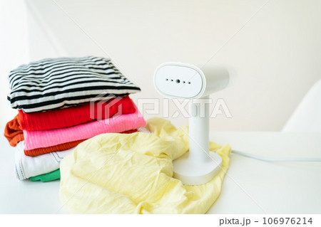 The steamer is on the table along with mint and ironed clothes on the table. Homework. 106976214