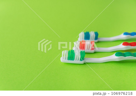 Three multi-colored toothbrushes on a light green background. Oral care concept. Place for inscriptions. 106976218