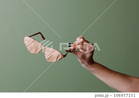 Female hand holds a brand new glasses wrapped in rustic beige craft paper. Black Friday shopping concept. Female hand holds a brand new glasses wrapped in rustic beige craft paper. Black Friday shopping concept. 106977151
