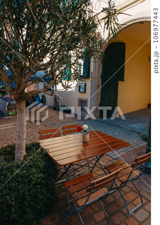 Empty cafe terrace with white table and chair. exterior of the cafe restaurant. interior Street cafe. Cozy street with flowers and French-style cafe table. Decor facade of coffeehouse with bike. Table Empty cafe terrace with white table and chair. exterior of the cafe restaurant. interior Street cafe. Cozy street with flowers and French-style cafe table. Decor facade of coffeehouse with bike. Table 106977443