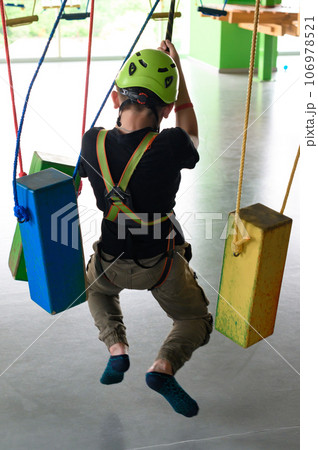 The boy actively and attentively passes the ropeway in the playroom. The boy actively and attentively passes the ropeway in the playroom. 106978521