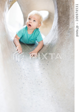 Child playing on outdoor playground. Toddler plays on school or kindergarten yard. Active kid on stone sculpured slide. Healthy summer activity for children. Little boy climbing outdoors 106978531