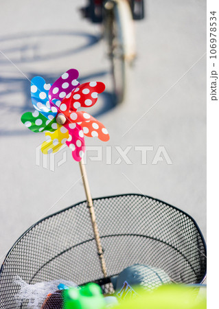 Colorful pinwheel attached to bicycle basket to entertain toddler child riding on front child seat on bike in summer 106978534
