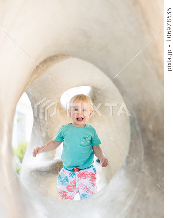 Child playing on outdoor playground. Toddler plays on school or kindergarten yard. Active kid on stone sculpured slide. Healthy summer activity for children. Little boy climbing outdoors 106978535