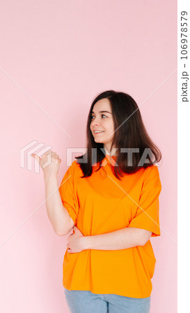 Alluring Advertising Space: Charming Lady Pointing Thumbs at Empty Area - Attention-Grabbing Concept Alluring Advertising Space: Charming Lady Pointing Thumbs at Empty Area - Attention-Grabbing Concept 106978579