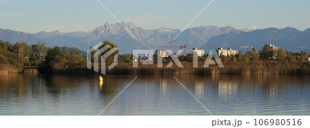 Houses in Wetzikon, shore of Lake Pfaeffikersee and mountain ranges in autumn. 106980516