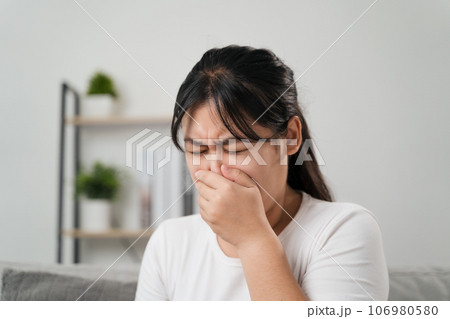 Young woman got a nose allergy sneezing sitting on the sofa at home. Flu, Influenza, Sick, Fever, Illness. Healthcare and medical concept. Young woman got a nose allergy sneezing sitting on the sofa at home. Flu, Influenza, Sick, Fever, Illness. Healthcare and medical concept. 106980580
