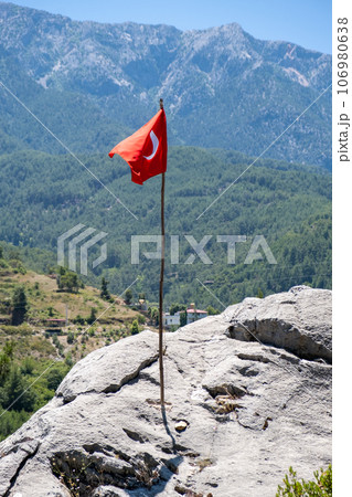 The Turkish flag is flying against the backdrop of beautiful mountains. The waving Turkish flag. The flag of Turkey on a flagpole with a copy space. 106980638