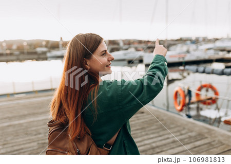 Redhead 30s women pointing finger. Woman Searching locations, walking along the waterfront, seaside. 106981813