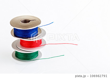 spools of thread in blue, red, green colors on a white background spools of thread in blue, red, green colors on a white background 106982791