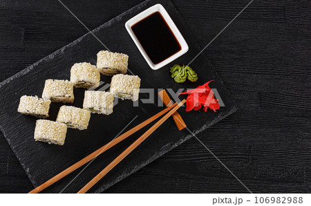 Sushi with salmon on a white plate with wasabi, ginger, soy, chopsticks on a black background 106982988