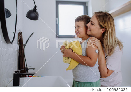 The diabetic boy getting ready for the day, in the morning, while wearing a continuous glucose monitoring sensor on his arm. 106983022