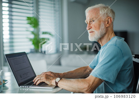 Senior man in a wheelchair working during retirement. 106983120