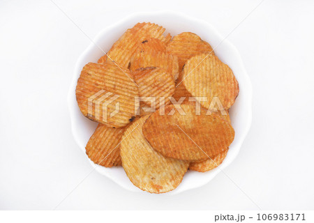 Red pieces of fried potatoes in a plate. Peppery chips on a white background. 106983171