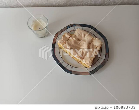 A piece of white cake on a plate. On a light background near a white wall. A piece of white cake on a plate. On a light background near a white wall. 106983735