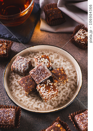 Sugar free candies made from fruit paste, nuts and sesame seeds on a plate vertical view Sugar free candies made from fruit paste, nuts and sesame seeds on a plate vertical view 106984366
