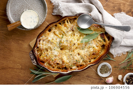 Potato gratin with sage and basil in the baking dish on wooden table, top view Potato gratin with sage and basil in the baking dish on wooden table, top view 106984556