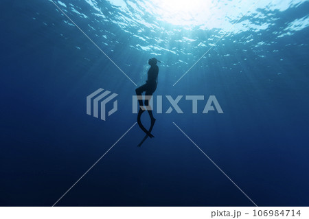 Freediver Swimming in Deep Sea With Sunrays. Young Man DIver Eploring Sea Life. 106984714