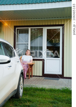 woman on the terrace with place to relax in fresh air in front of motel houses. 106985183