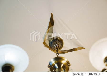 A torn stretch ceiling with a ceiling lamp  106985192